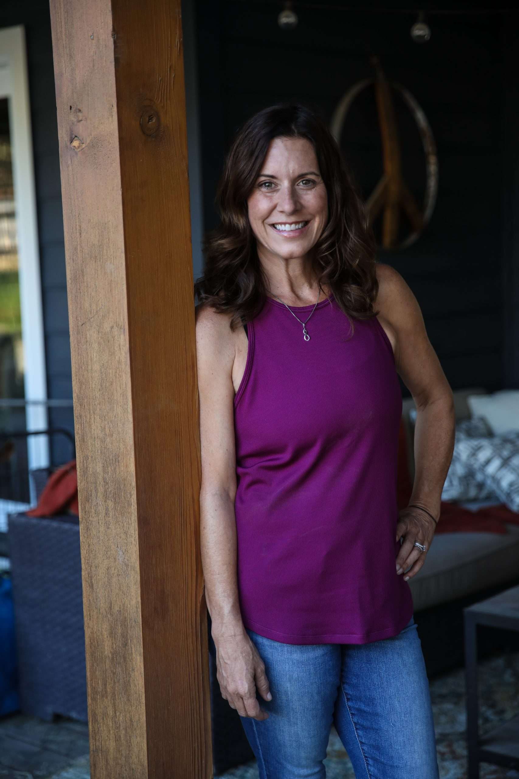 Denise Beringer leaning on a beam with a smile on her face