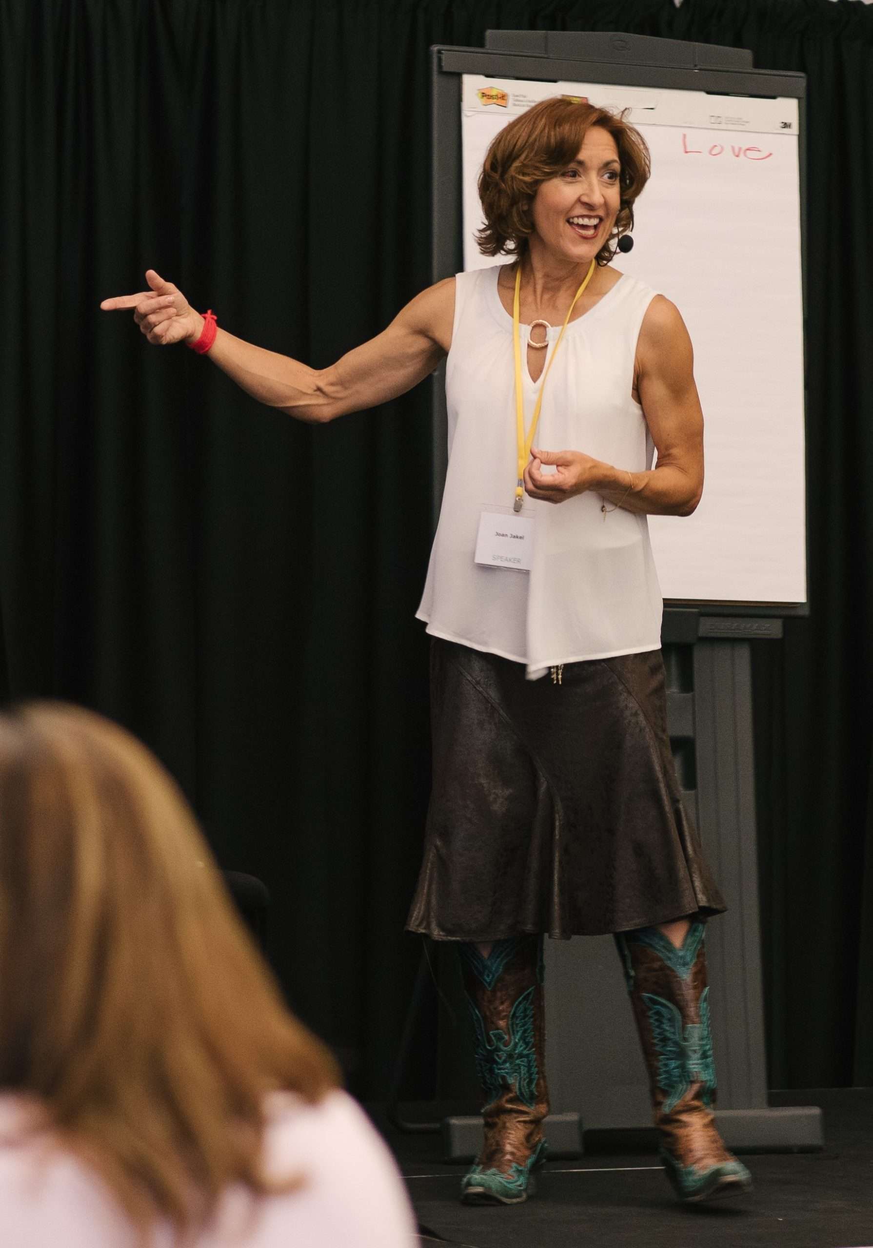 Joan Jakel, personal development coach, on stage coaching a room of people