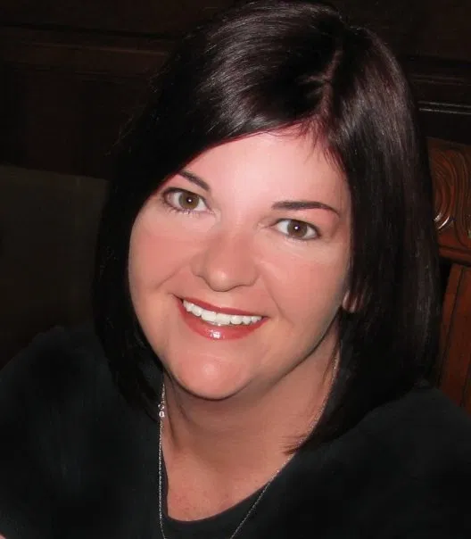 Denise Beringer leaning on a beam with a smile on her face