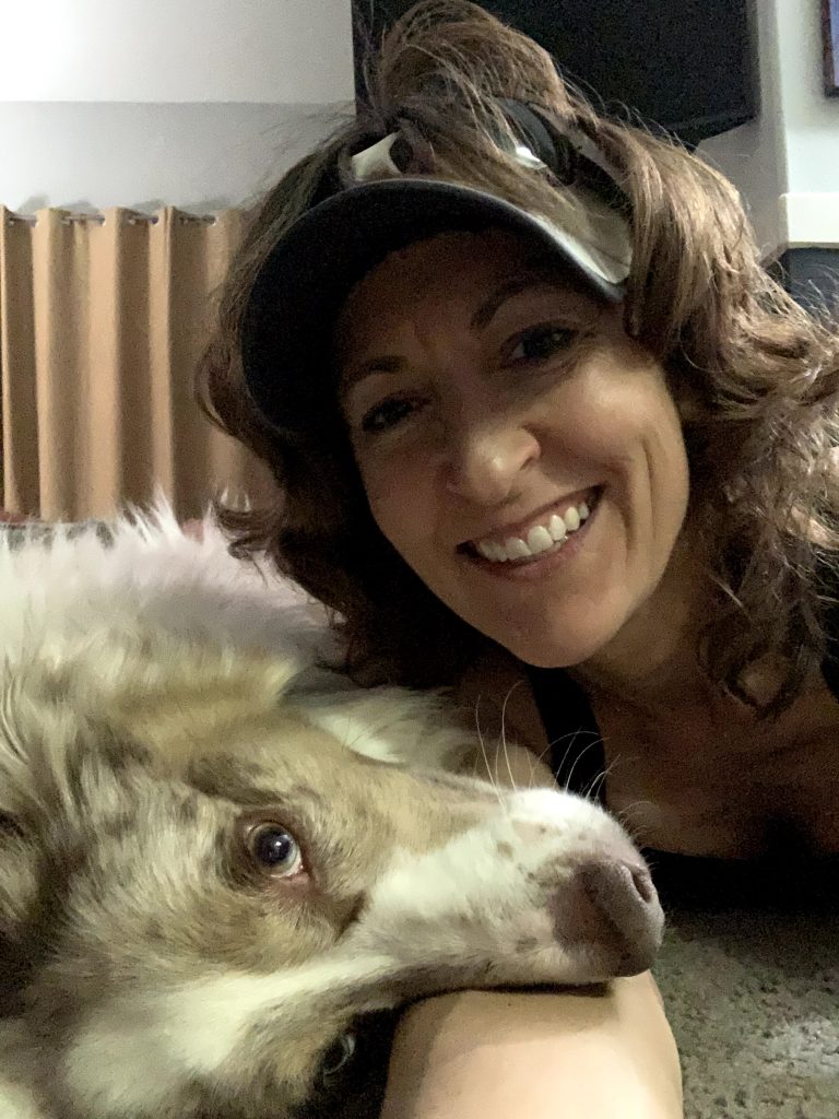 Coach Joan Jakel with her Australian Shepherd dog, Rolo, cuddling in a fun moment